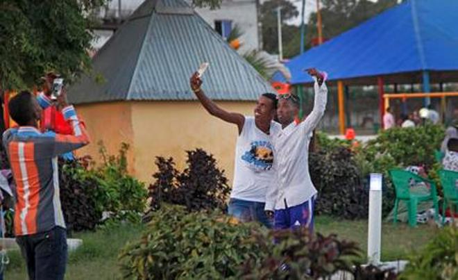 In this photo taken Sunday, Aug. 21, 2016, young Somali men take selfies in the Peace Garden public park in Mogadishu, Somalia. War-weary Somalis are trying to relax and rebuild their country after decades of violence, but the homegrown Islamic extremists al-Shabab keep striking at the heart of its seaside capital, killing scores of people so far this year. (AP Photo/Farah Abdi Warsameh)